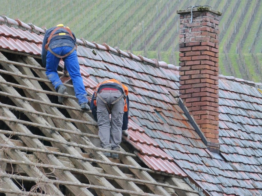 Two workers repairing a tile roof